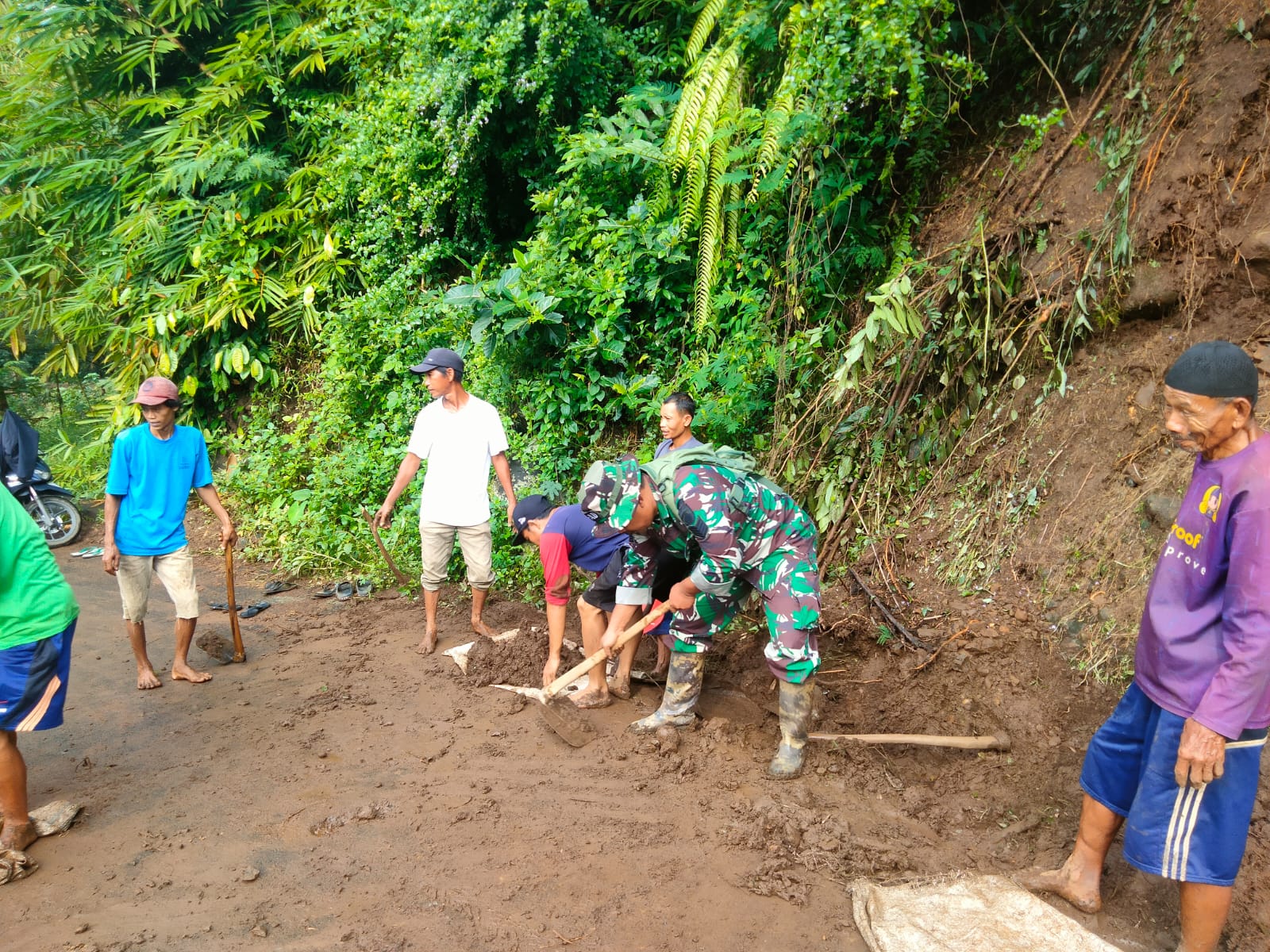 Babinsa Gotong Royong Bersihkan Material Tanah yang Menutup Akses Jalan Penghubung Desa